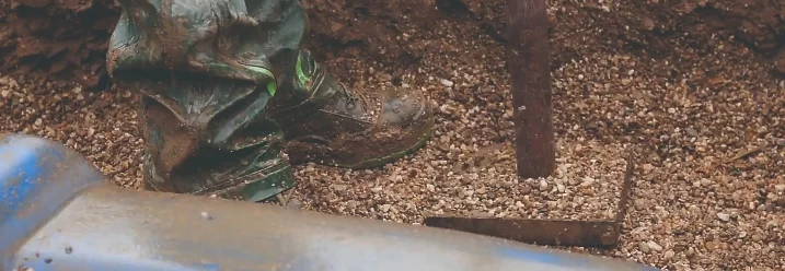 Person glättet Grubenboden mit einem Handstampfer